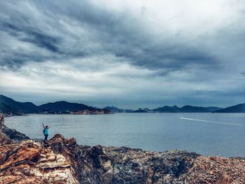 Rear view of man standing by sea against sky