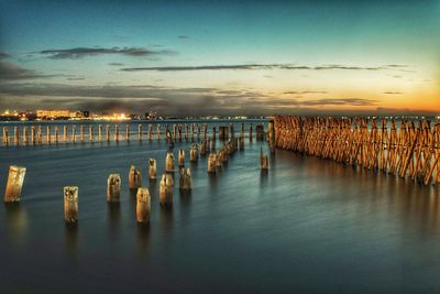 Pier on sea against sky at sunset