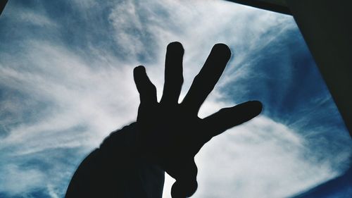 Low angle view of cropped hand against sky