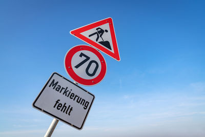 Low angle view of road sign against blue sky