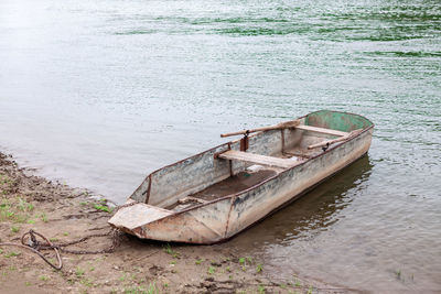 Moored rusty metal boat with oars . fishing village