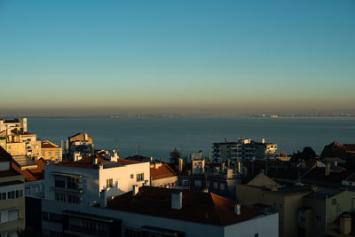 High angle view of townscape by sea against clear sky