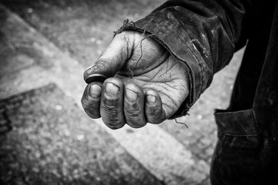 Cropped hand of beggar holding coin on footpath