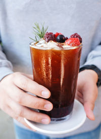 Midsection of  man holding a glass of mixed berry soda and espresso shot with fresh fruit mixes.