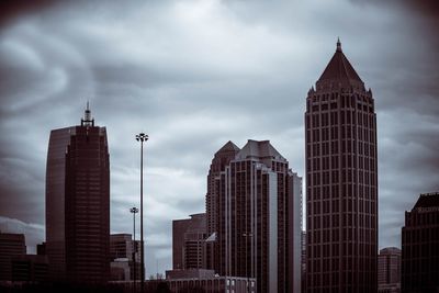 Low angle view of skyscrapers against cloudy sky