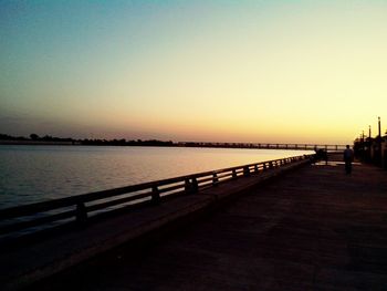 Pier in sea at sunset