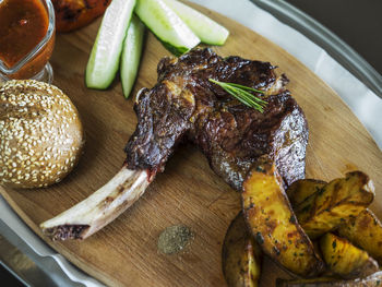 Close-up of grilled chicken with burger and french fries on cutting board