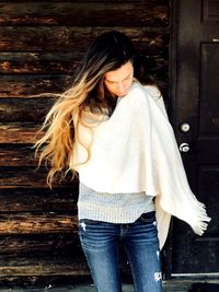 Young woman with scarf standing against wall