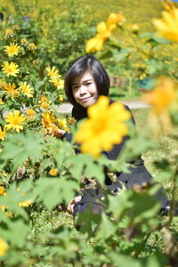 Portrait of young woman yellow flowering plants
