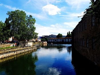 Canal amidst buildings against sky in city