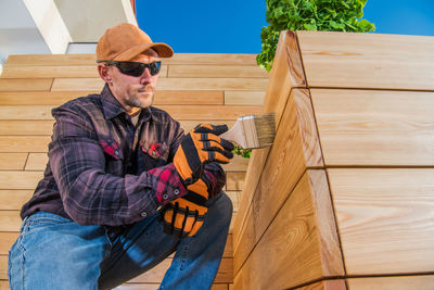 Man wearing sunglasses sitting on wood