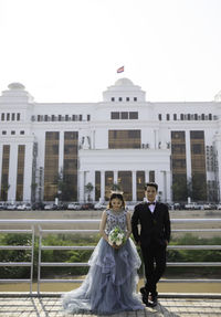 Man and woman holding umbrella against building