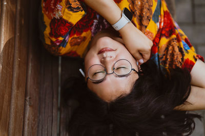 Relaxed asian woman listening to music on headphones while lying on park bench