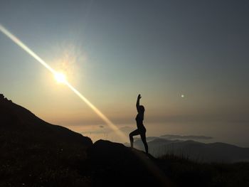 Silhouette person standing on mountain against sky during sunset