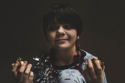 Portrait of woman holding camera over black background