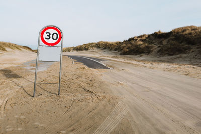 Road sign on field against clear sky