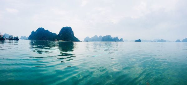 Scenic view of sea by mountain against sky