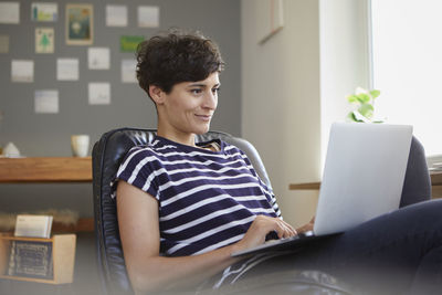 Smiling woman using laptop at home