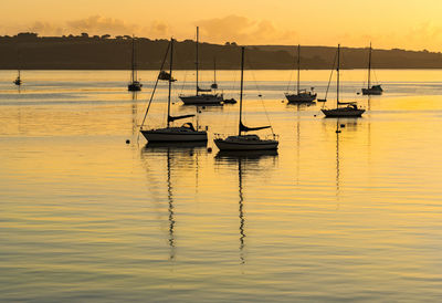 Boats moored on sea against sky during sunset