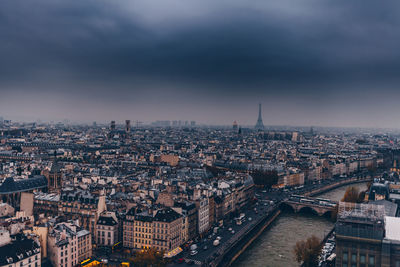 High angle view of city buildings against cloudy sky