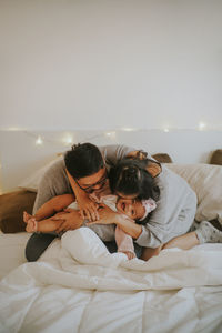 Rear view of people relaxing on bed