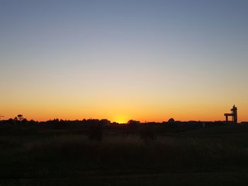 Scenic view of silhouette field against clear sky during sunset