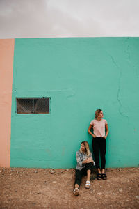 Full length of women standing against wall