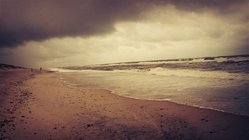 Scenic view of beach against cloudy sky