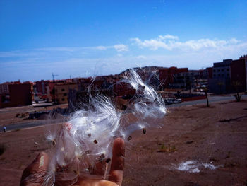 Close-up of hand splashing water against sky