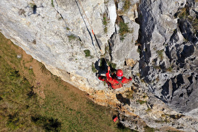 Aerial view of mountain rescue exercise on a rocky wall, rescuer hanging on rope