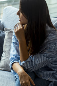 Young woman sitting on sofa at home