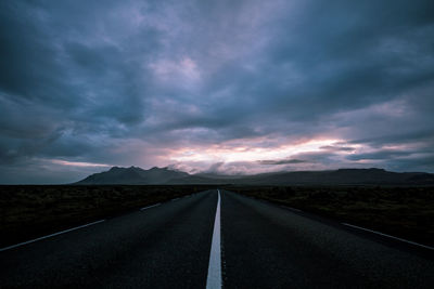 Empty road along landscape at sunset