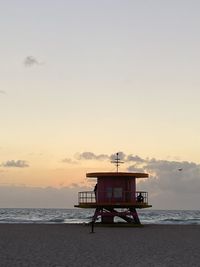 Lifeguard hut on beach against sky during sunset