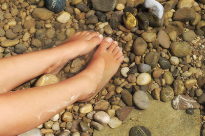 Low section of woman on pebbles at beach