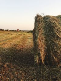 Hay bales on field against clear sky