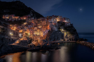 High angle view of townscape by sea against sky at night