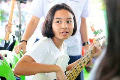 Girl looking away while playing guitar