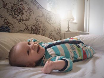 Baby lying down while laughing on bed in bedroom