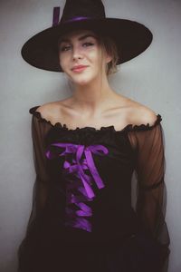 Young woman wearing witch hat against gray background