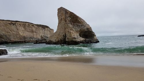 Rock formation on beach against sky