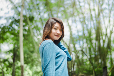 Portrait of smiling young woman standing in forest