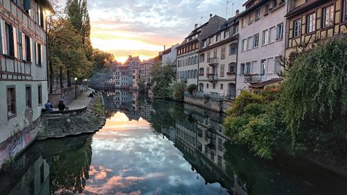 Canal amidst buildings against sky during sunset