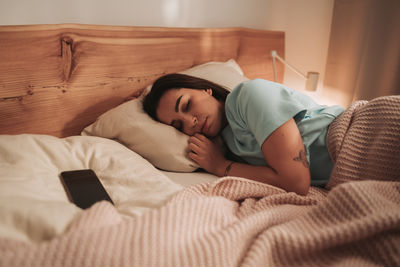 Portrait of woman lying on bed at home