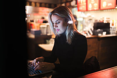 Young woman using laptop while sitting at table