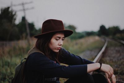 Young woman looking away while sitting on railroad track