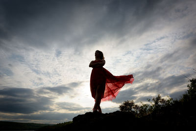 Low angle view of woman standing against sky during sunset