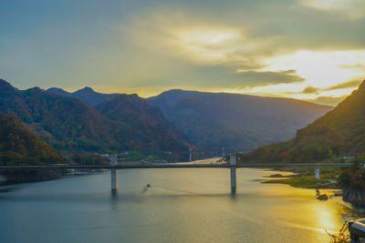 Scenic view of road by mountains against sky during sunset