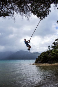 Man jumping over sea against sky