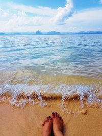 Low section of woman on beach against sky