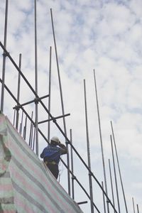 Low angle view of man standing on scaffolding against sky